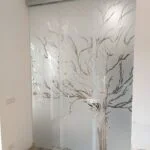 pareti divisorie in vetro a tre ante con decorazione di un albero