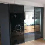 cucina divisa dal soggiorno tramite divisorio in vetro nero scorrevole
